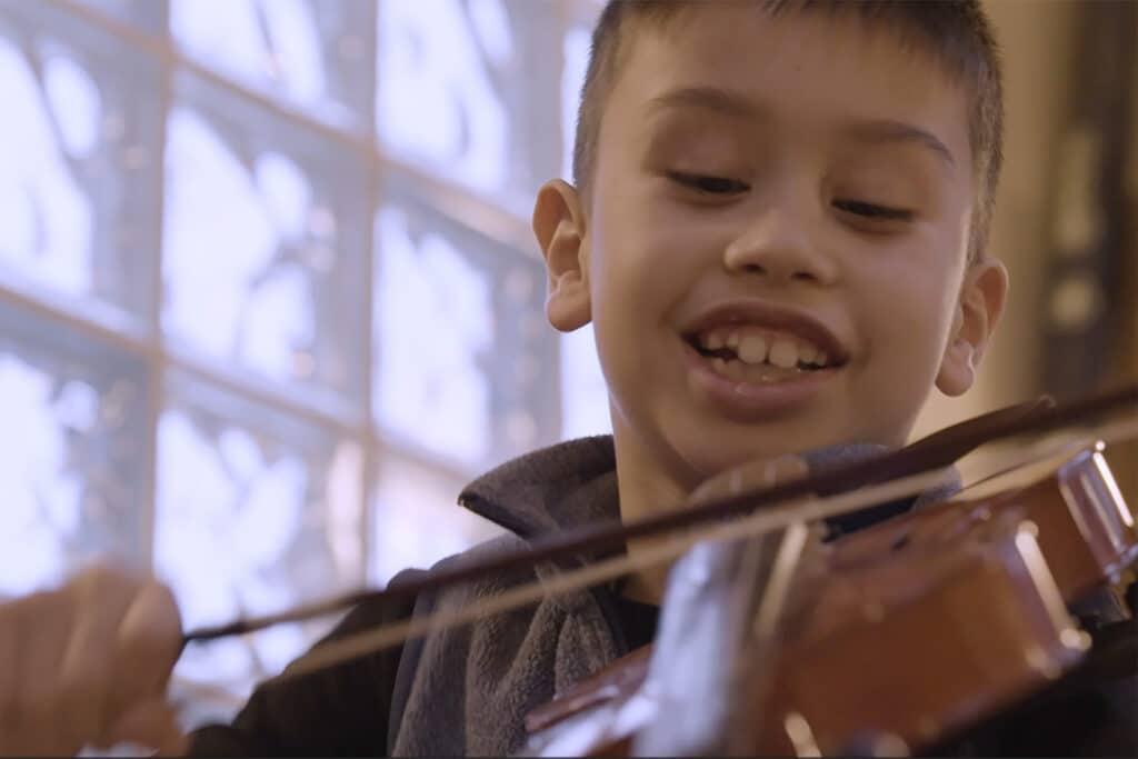 Nigel playing a violin in his music therapy class