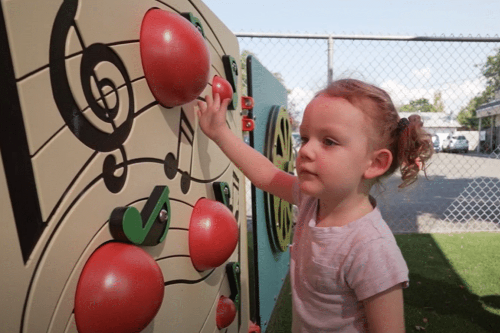 Skylar, a little girl with pony tails, plays in a park. Thanks to an autism assessment, she now has access to critical autism resources through government funding.