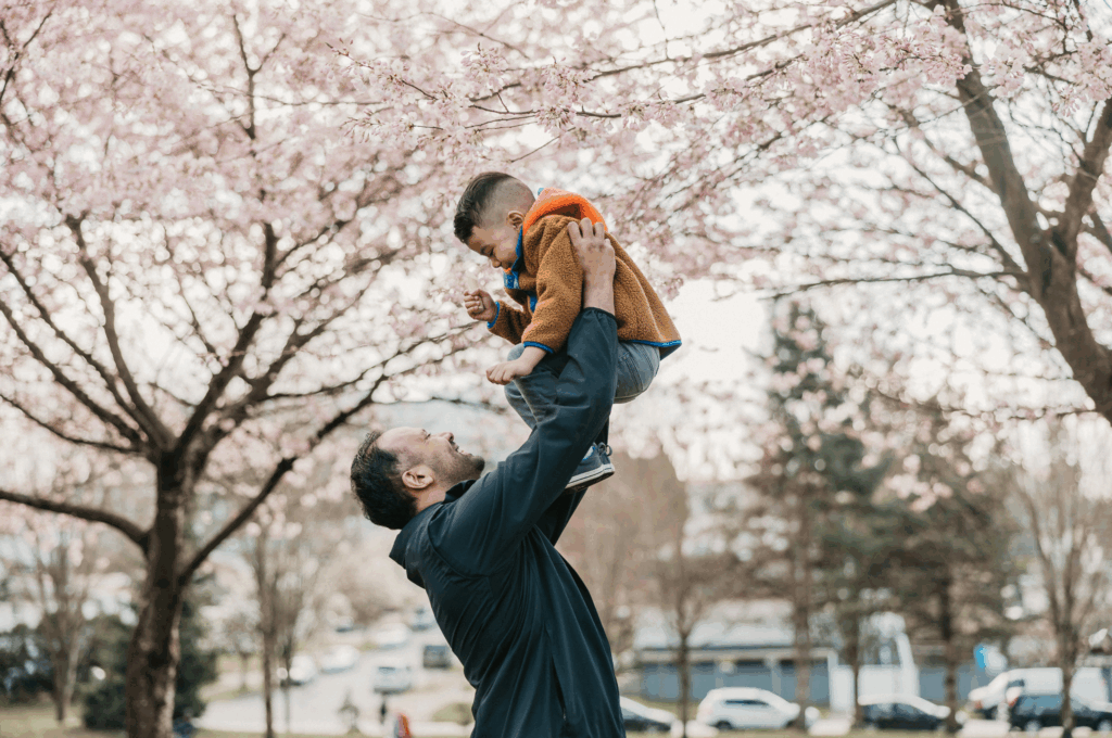 Dads like Will are champions for their kids, ensuring they get the supports they need. Will is pictured laughing as he holds his son Asher above his head.